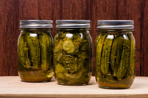 pickled cucumbers with celery in jars on the table