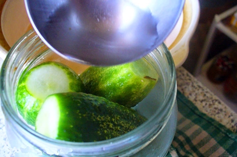 cucumbers in apple juice in a jar on the table